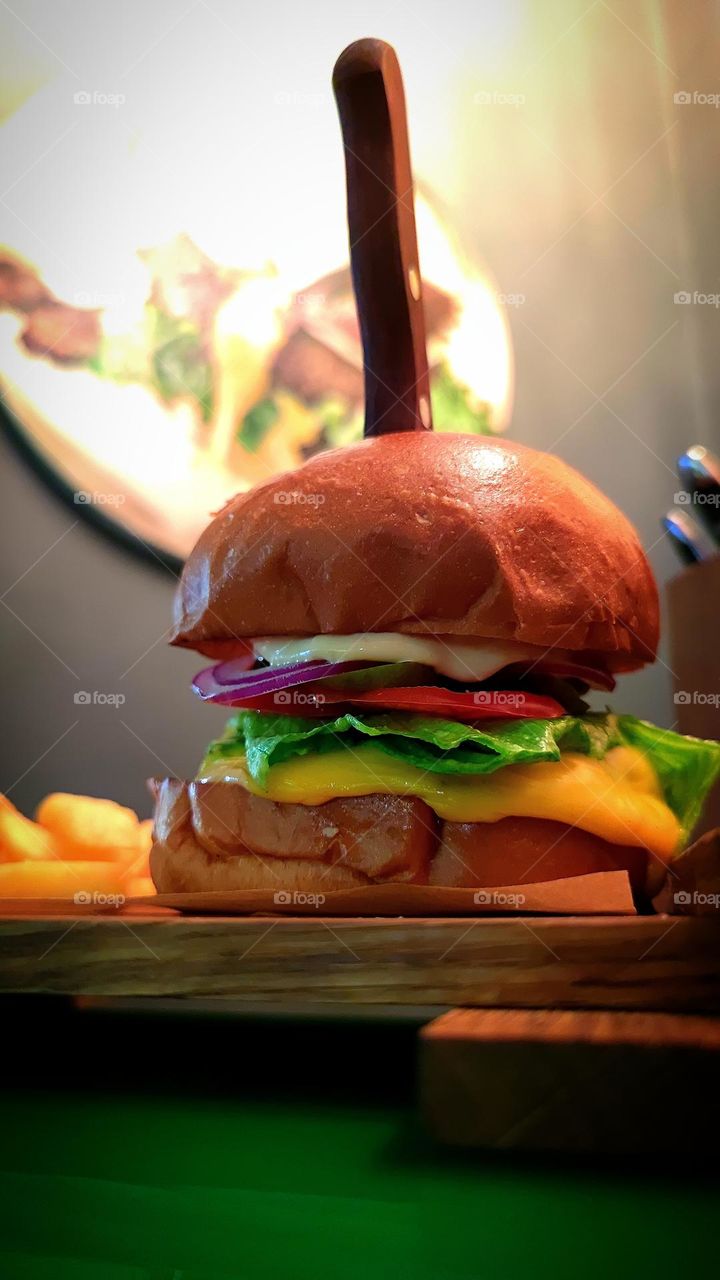 Juicy hamburger on a wooden board. Serving - pierced with a knife