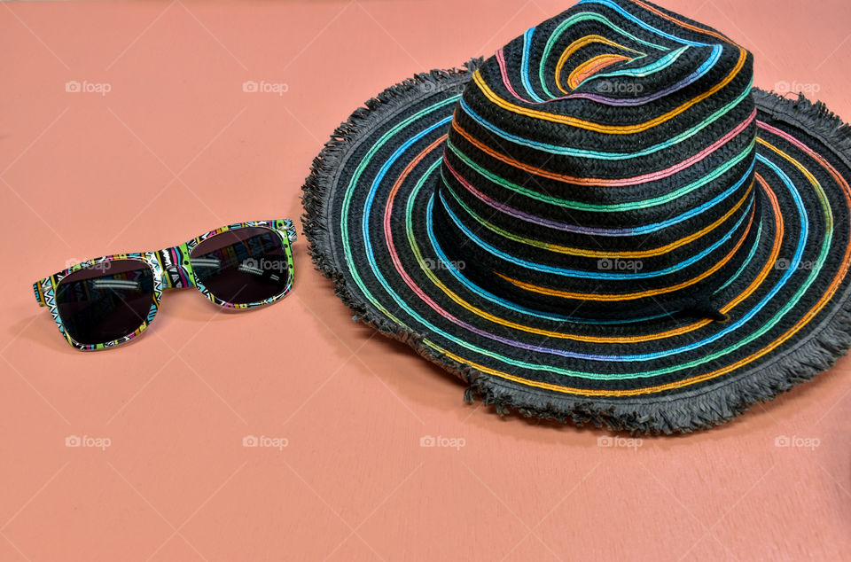 Colorful hat and sunglasses on the pink background 