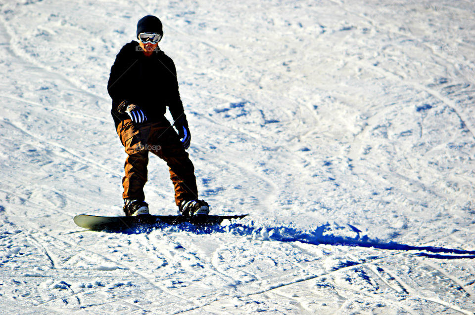 A young man snowboards down a mountain of snow