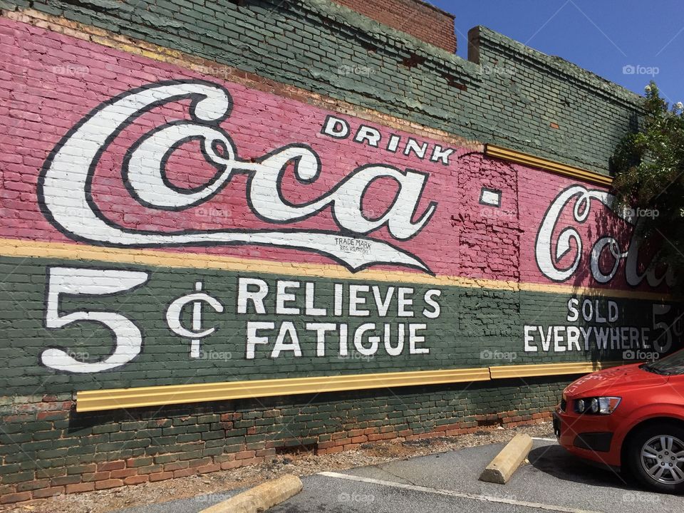 Big Coca Cola old painting on an old brick building wall.