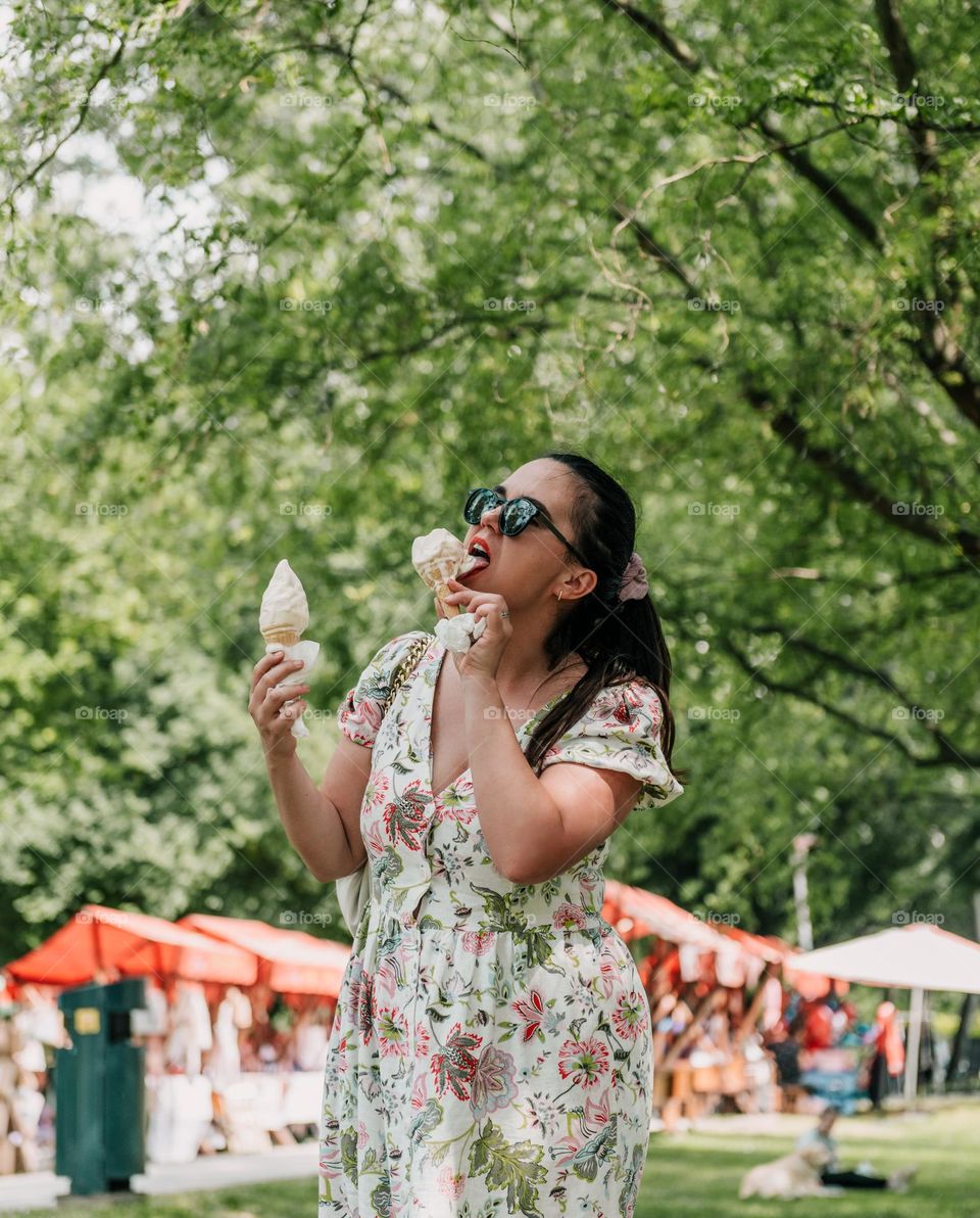 Young woman eating ice cream in park in city