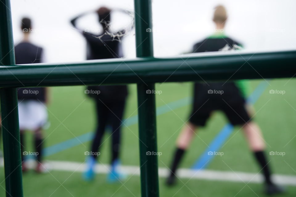 Young people on a football pitch with bars behind them 