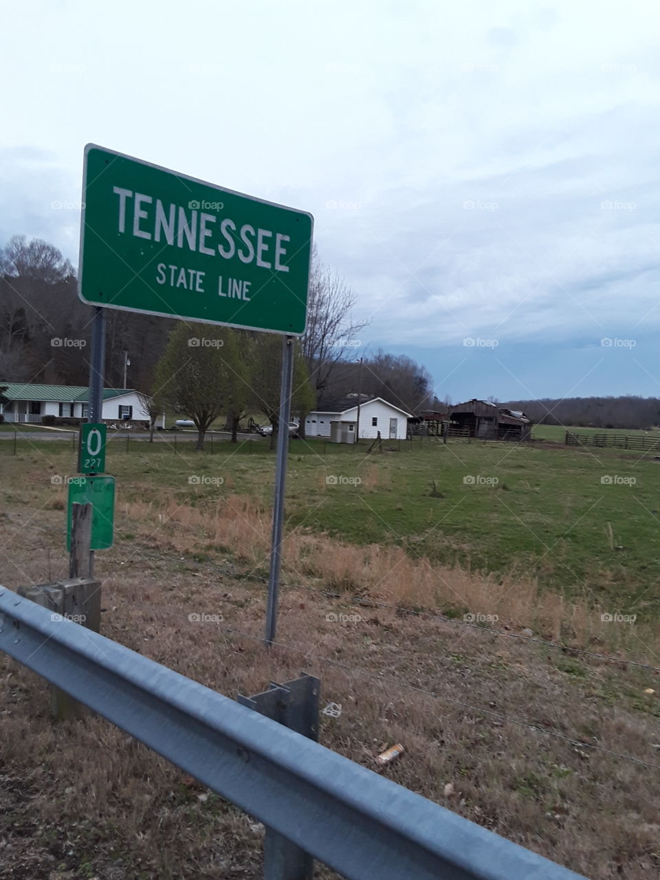 The Tennessee State Line in rural North Alabama with farm house and fields.