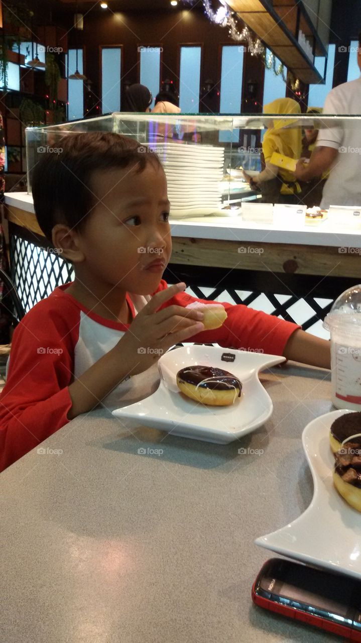 Boy eating donuts in restaurant