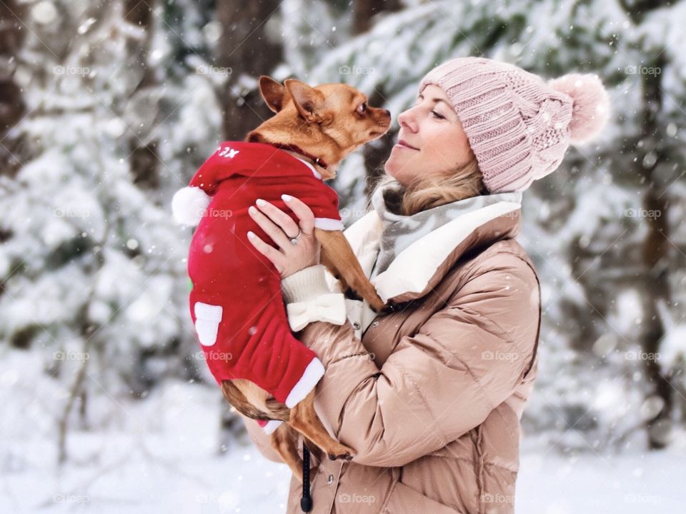 woman with small dog in snowy forest in winter