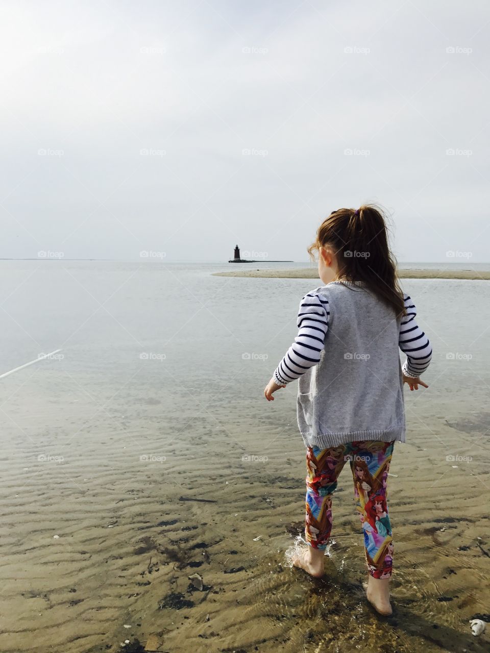 Little girl on the beach with a lighthouse