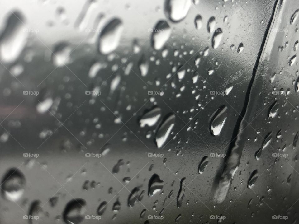 Rain water drops on a window, some in focus while others are blurred