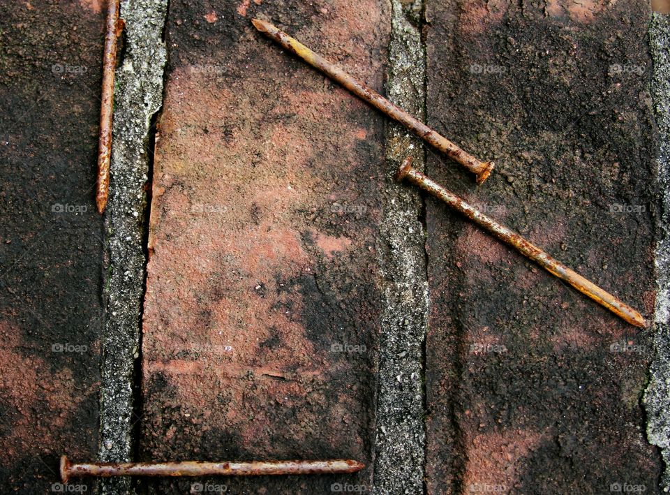 old nails rusting on a brick wall.