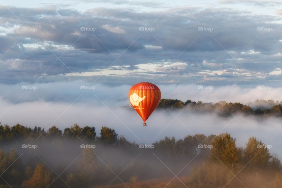 Hot air balloon ride over the beautiful landscape of Trakai in Lithuania with fog over the trees.