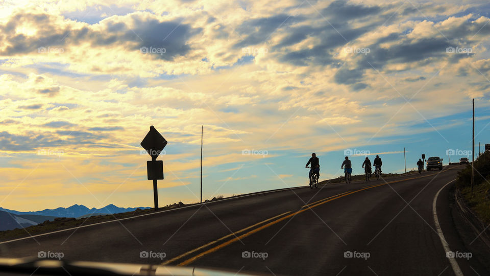 Silhouettes of mountain bicycle riders, with beautiful sunset sky background. Rock Cut, Trail Ridge Road, Rocky Mountain National Park, USA. Active healthy outdoor lifestyle concept.
