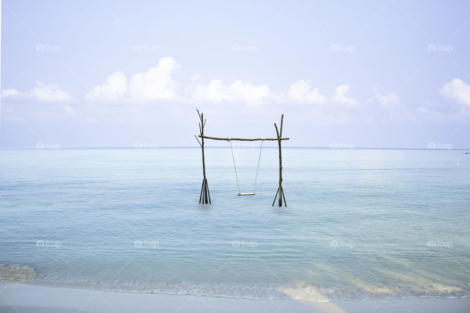 Swing chairs made from wood in the sea Background sky and cloud.