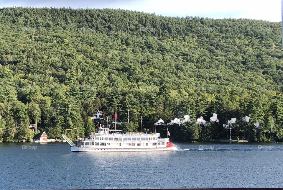 A sightseeing craft sailing by in Lake George NY with the Adirondacks behind. 