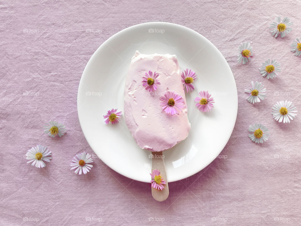Pink fruit ice cream on white plate with white and pink flowers 