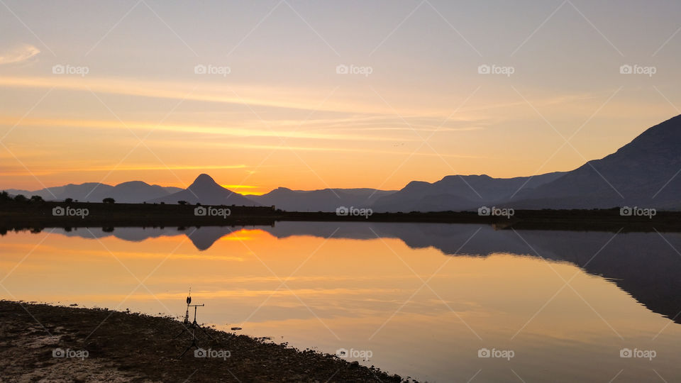 sunset behind mountains and over water