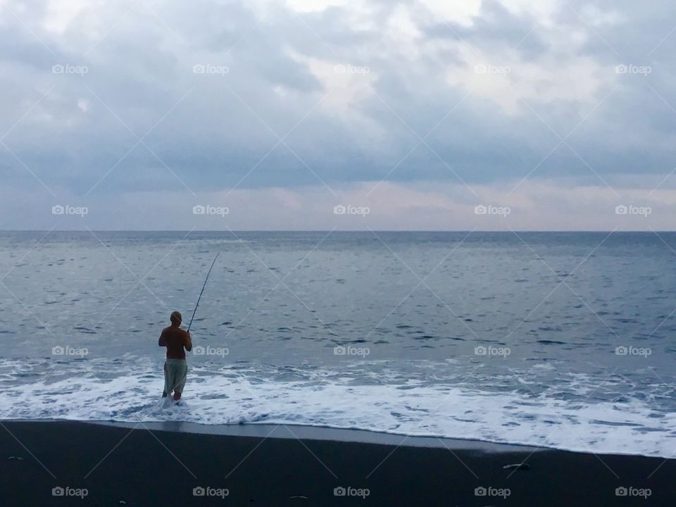 Fisherman on the black sand beach