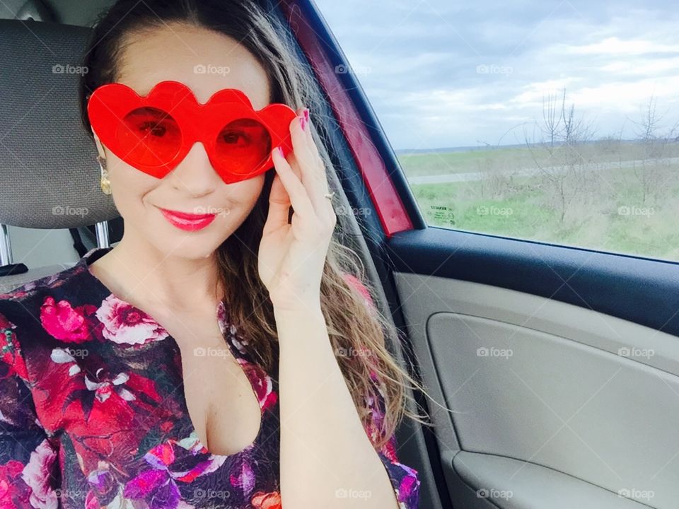 Selfie of woman in the car wearing heart-shaped sunglasses