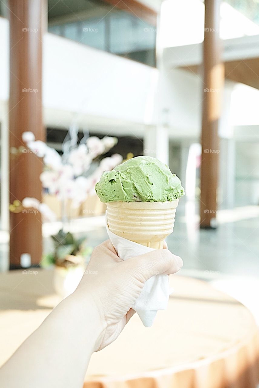 Japanese matcha green tea ice cream. A hand holding an ice cream cone. 