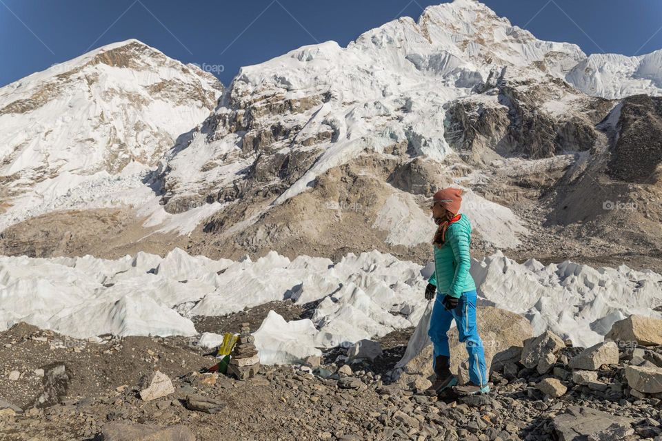 Woman standing in front of the Himalayan mountains, at the foot of Everest mountain; while being on a hike to the Everest Base Camp.