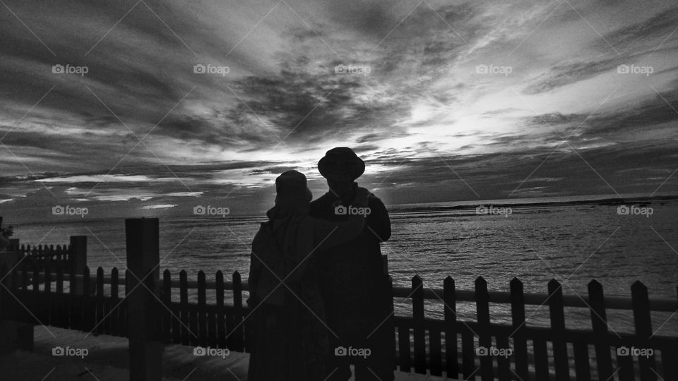 silhouette couple standing by railing against sea