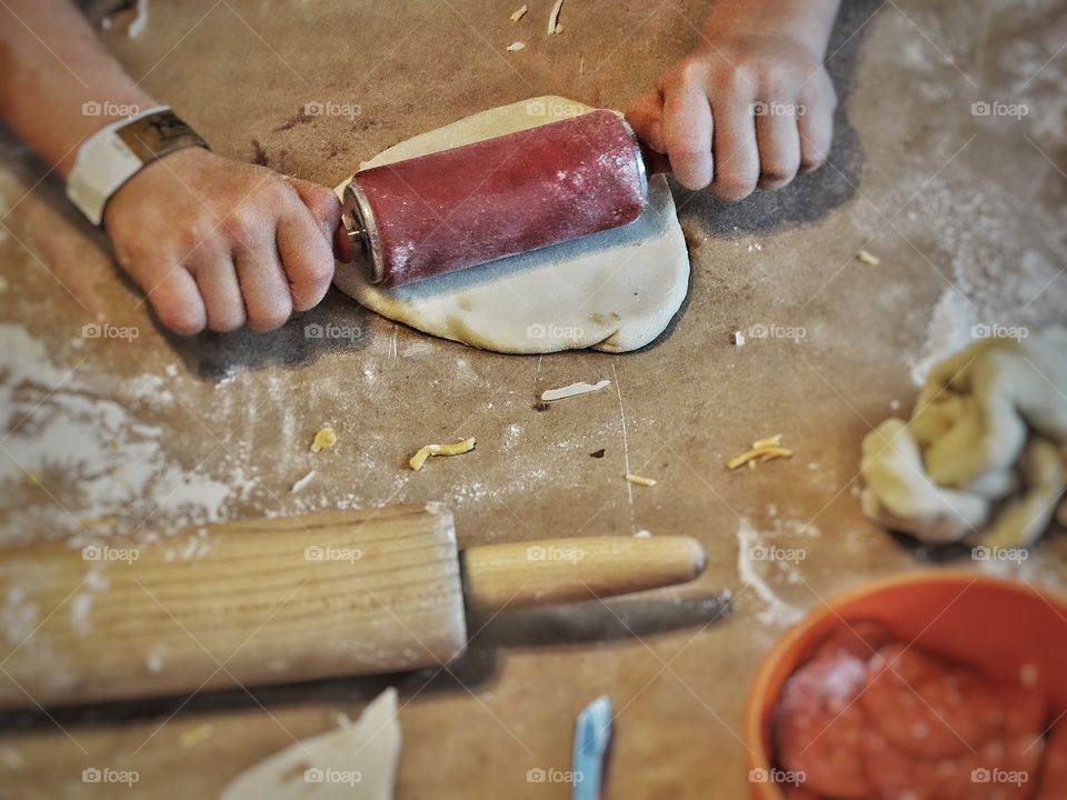 Baker flattening bread dough with a rolling pin
