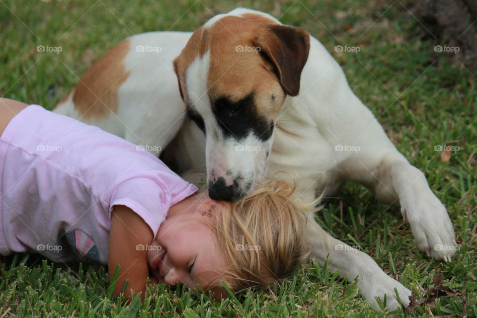 Toddler playing with dog in grass