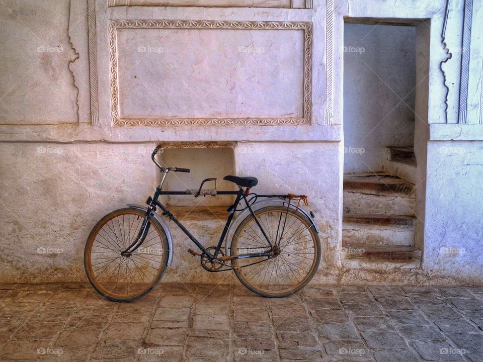 Bike-stall. . This shot was made in Uzbekistan. I saw a man riding that bike with a little boy who was seating in front of him on that small saddle. They were going to the musk. The bike was left in a nearby building while they were praying. 