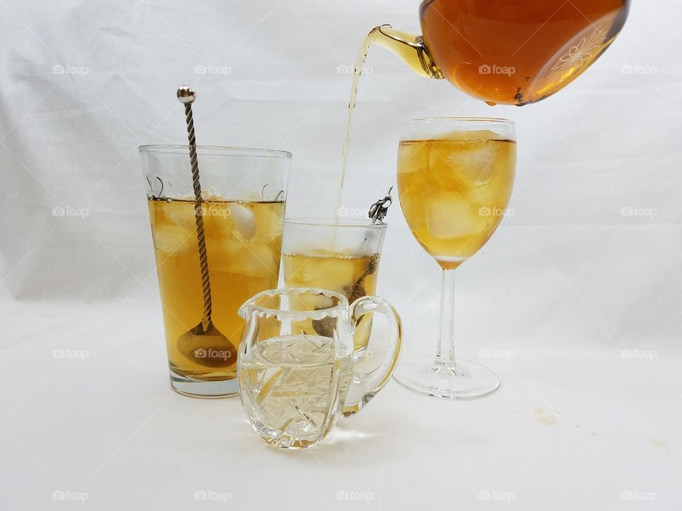 pouring tea over ice in a variety of glassware