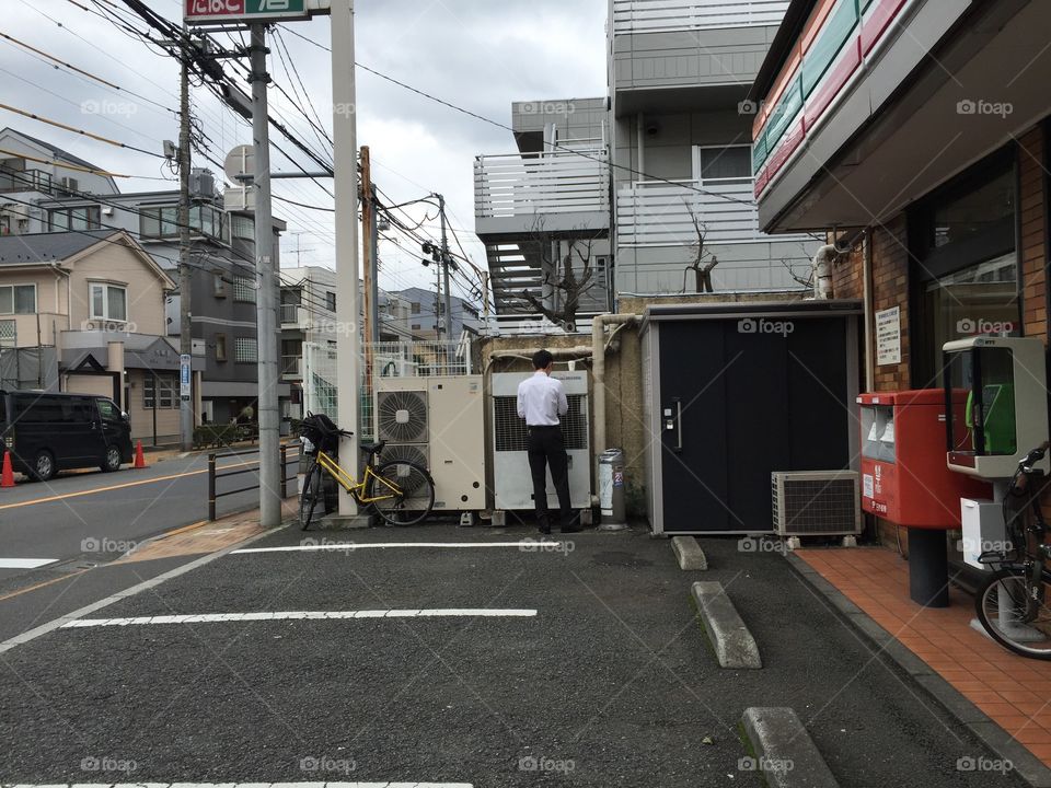 A salaryman in japan standing on the street in the middle of his coffee break