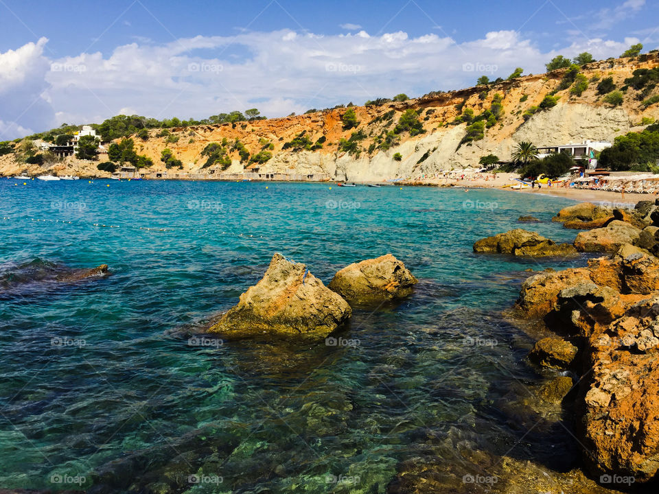 Island beach with rocks and blue sea in Ibiza, Spain
