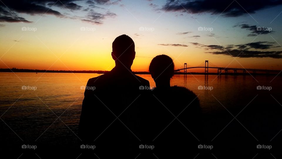 man and woman silhouette watching the sunset