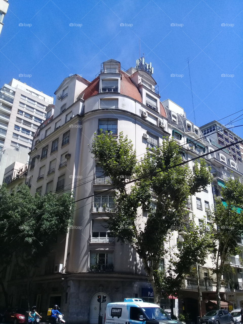 imagen de un antiguo edificio de departamentos situado en una vereda con árboles,en una esquina en diagonal sobre dos avenidas urbanas. Ciudad de Buenos Aires.