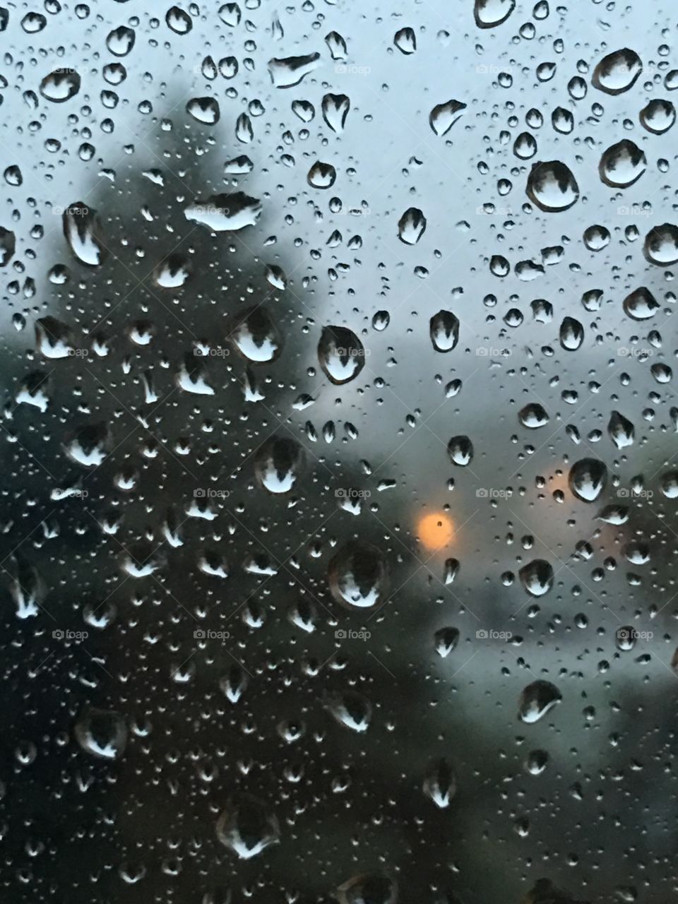 Focused on the droplets on the window with landscape in the perspective distance.