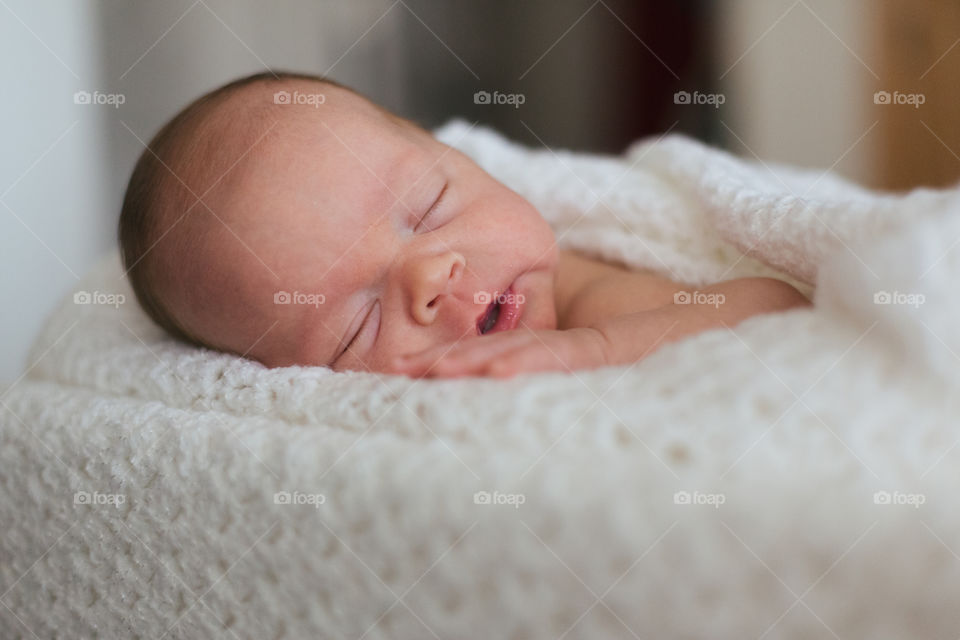 Newborn baby boy sleeping on a white blanket