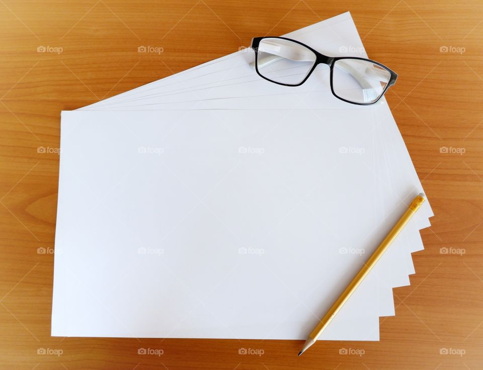 Blank paper for planning with handy pencil and glasses on wooden background.