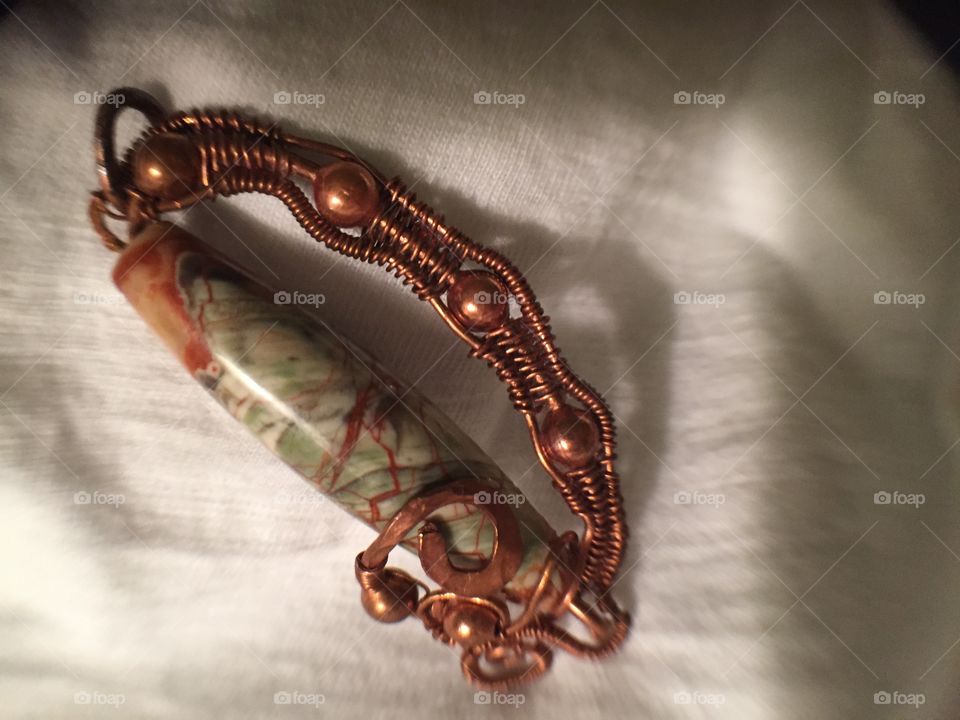 Copper wire wrapped oblong glass bead for a necklace.