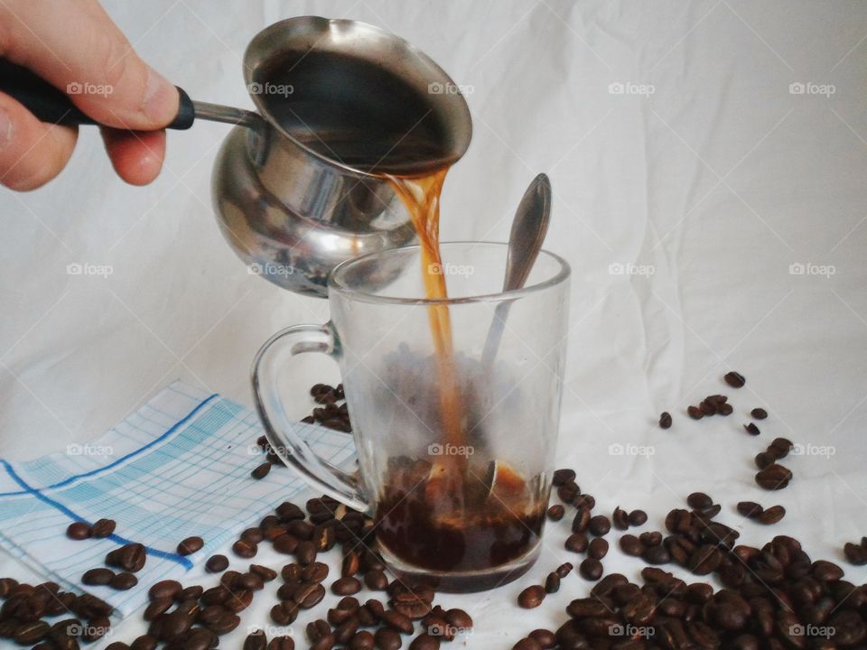 In a cup of coffee poured on the background of coffee beans