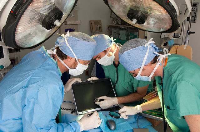 Three men operate on a computer in an emergency room at the hospital