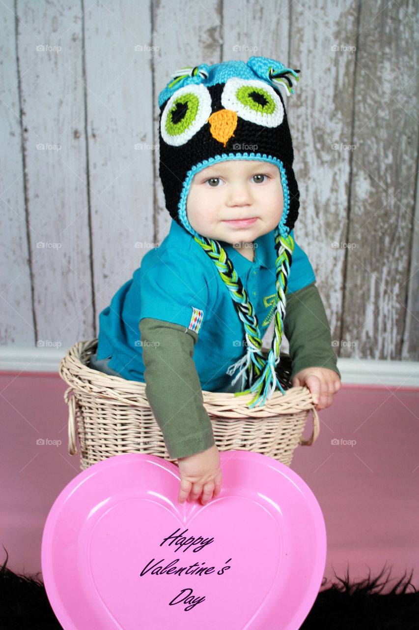 Little kid wearing knitted hat on wicker basket