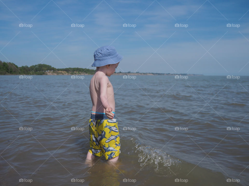 Toddler boy is enjoying the water at the beach shores of Port Burwell, Ontario, Canada.
