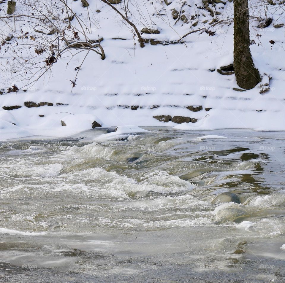 A creek still bubbles away in the middle of winter. Not far away, much of the water is frozen.