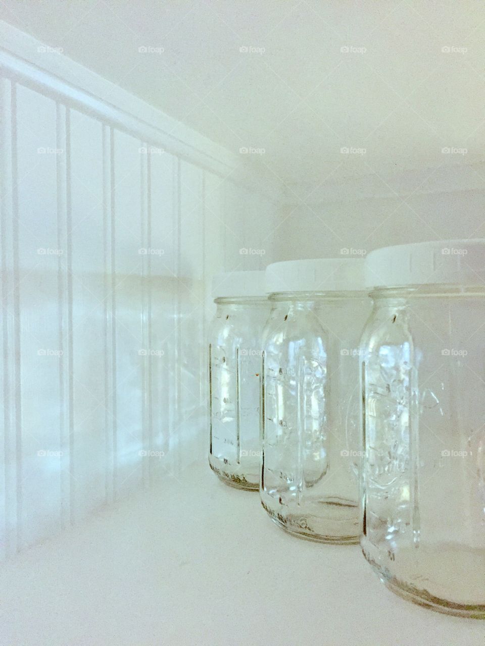 Minimalistic Snaps - light reflecting through a row of mason jars on a beadboard shelf