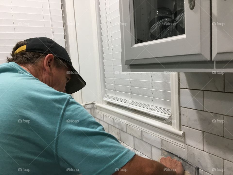Worker installing new tile backsplash 