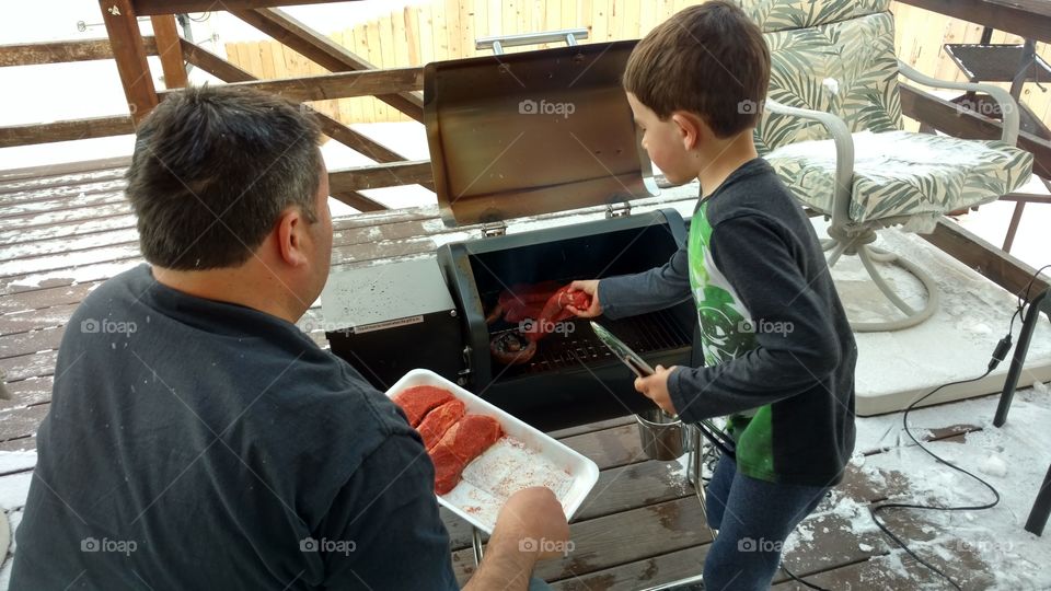 Father teaching son to barbeque.