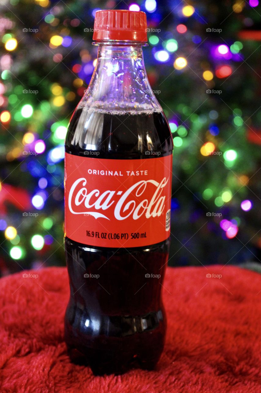 Coca Cola Bottle in Front of Multi Colored Lighted Christmas Tree