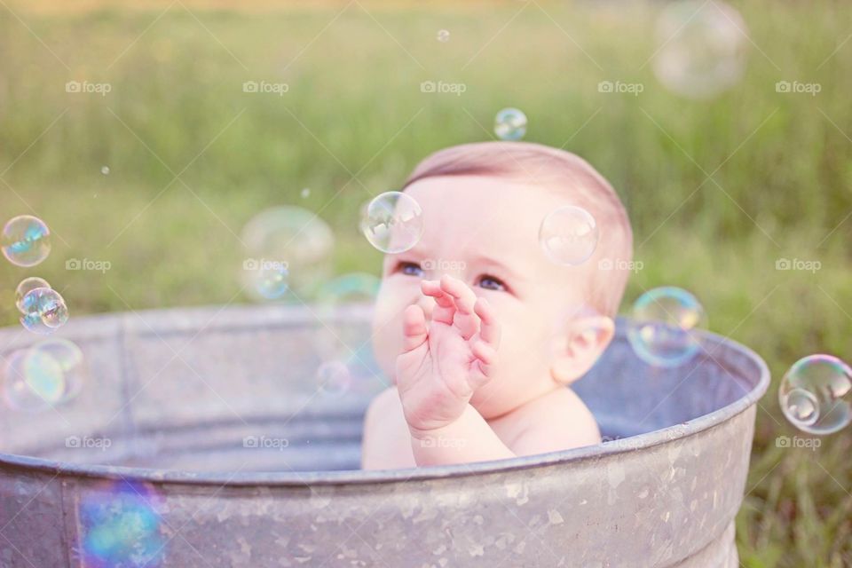 Pop. Baby in old wash basin popping bubbles