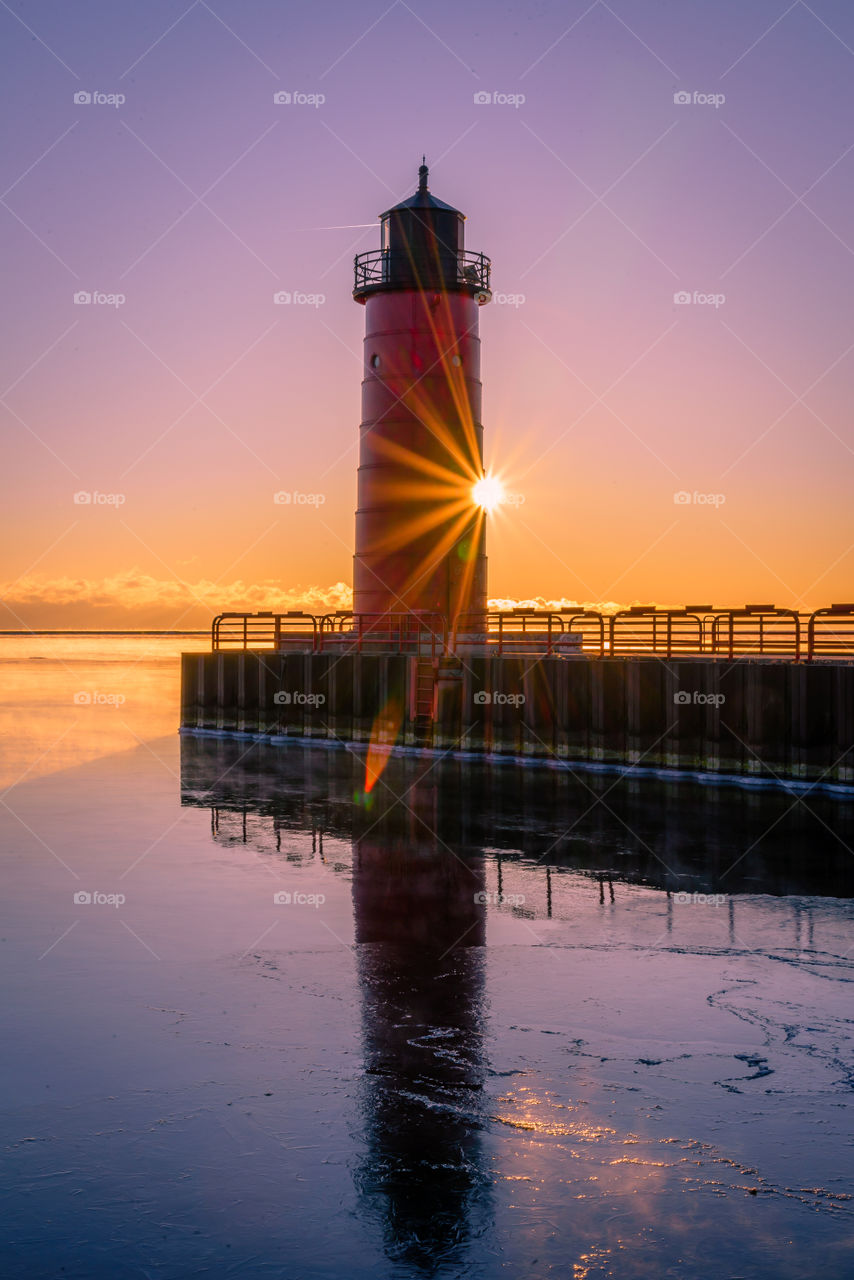 Sunrise on Lake Michigan with starburst and red lighthouse
