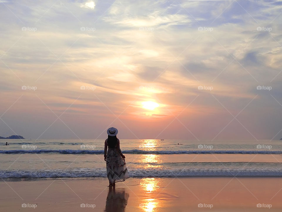 Young woman enjoying her summer tropical vacation and beautiful sunset above the sea 