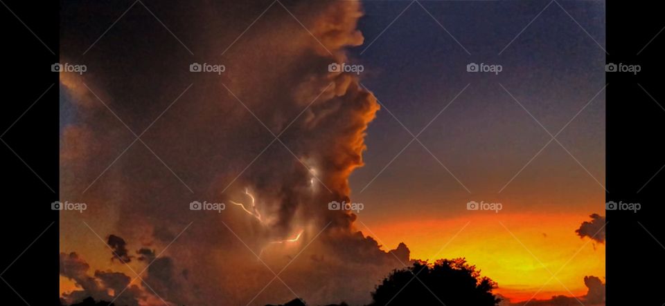 Cloud to cloud lighting in approaching thunderstorm on midwest prairie sunset 