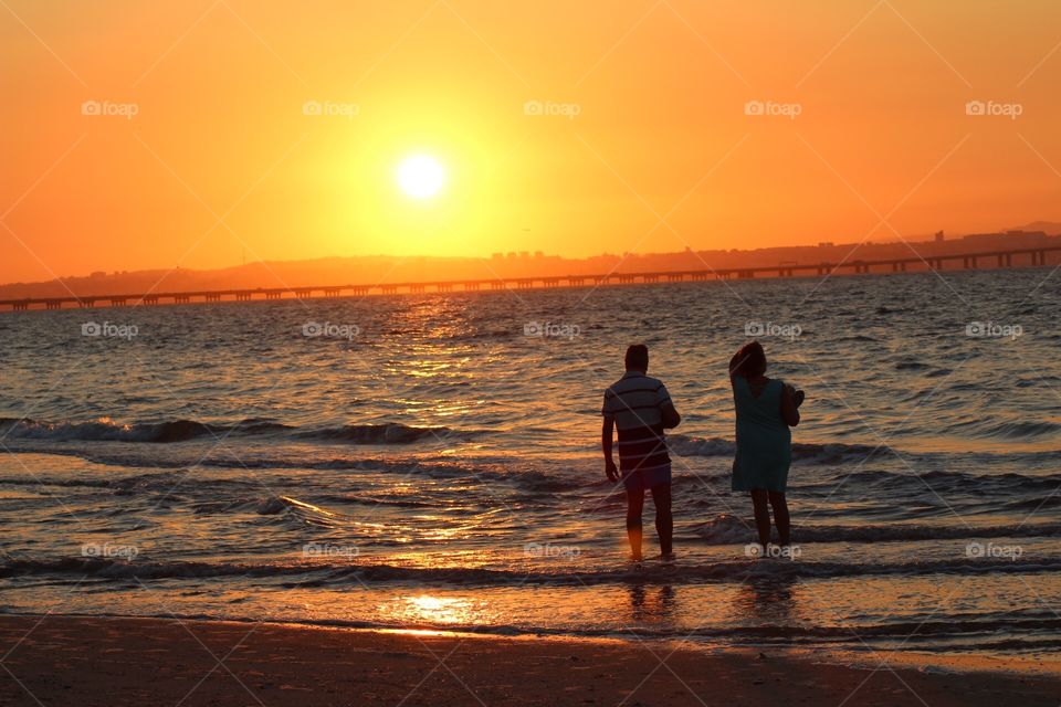 Couple watching the sunset by the seashore 