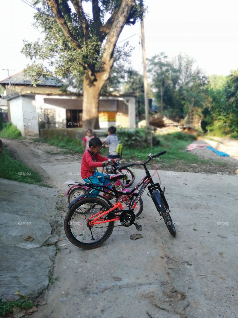 Kids are playing with their bicycle and enjoying childhood in native village.